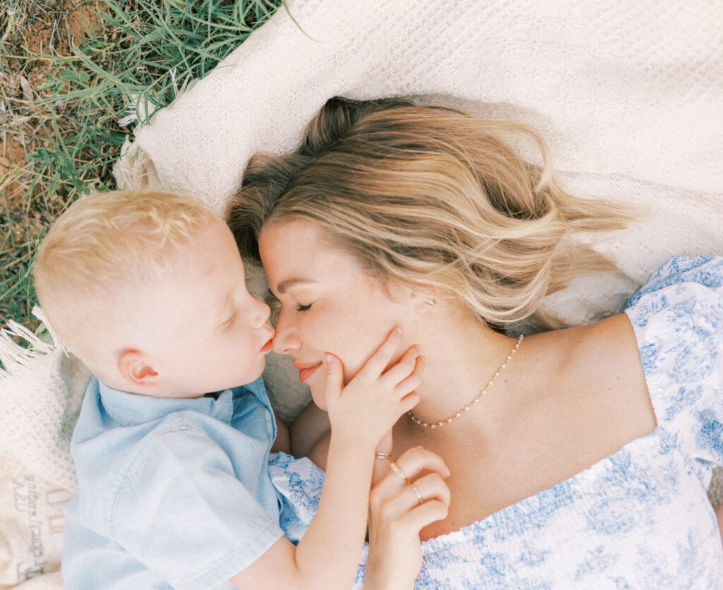 mom and son laying on the ground. son is kissing moms nose in Phoenix Arizona