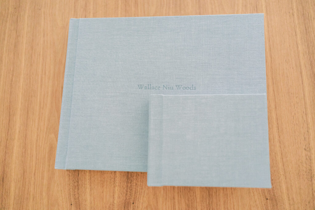 Large blue album on brown table with a smaller blue album laid on top of the larger one.