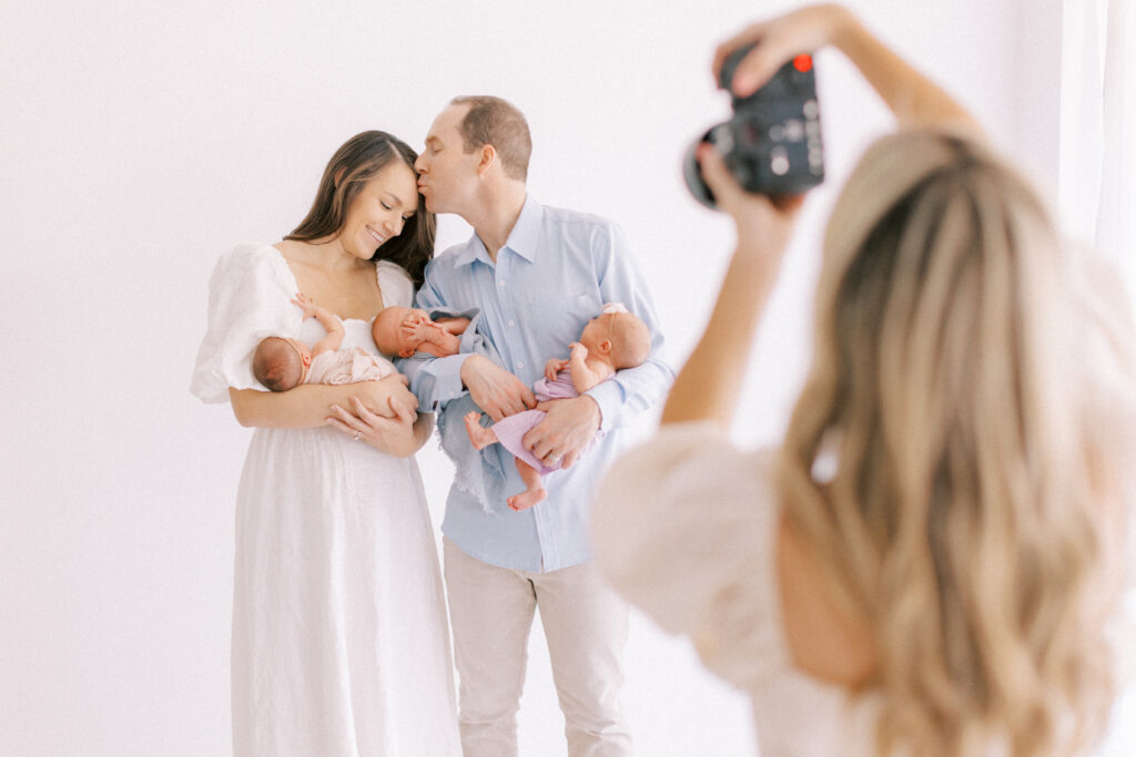 Nichole Pach Photography taking a photo of mom and dad holding their three triplets in scottsdale arizona.
