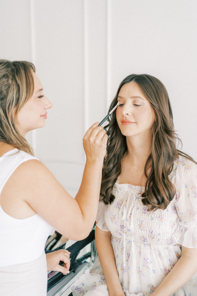 A mom in a light colored floral dress getting her makeup done in our newborn studio in phoenix Arizona.