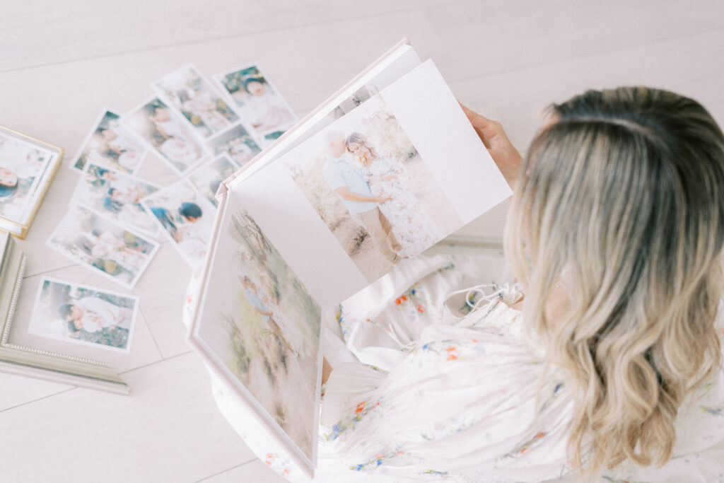 An open album showing a maternity session with someone looking at it.