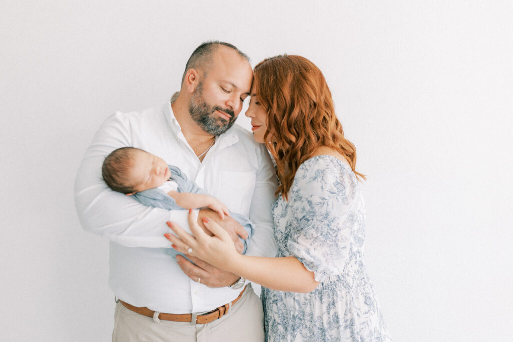 New mom and dad snuggling up holding their newborn baby boy in Scottsdale Arizona.