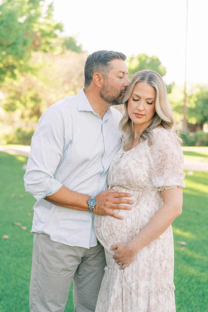 husband kissing pregnant wife on the side of the head in Mesa Arizona
